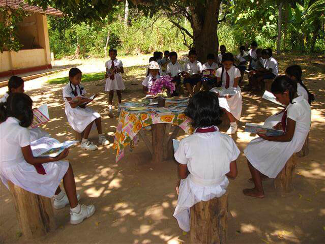 Children reading out in the school yard.
